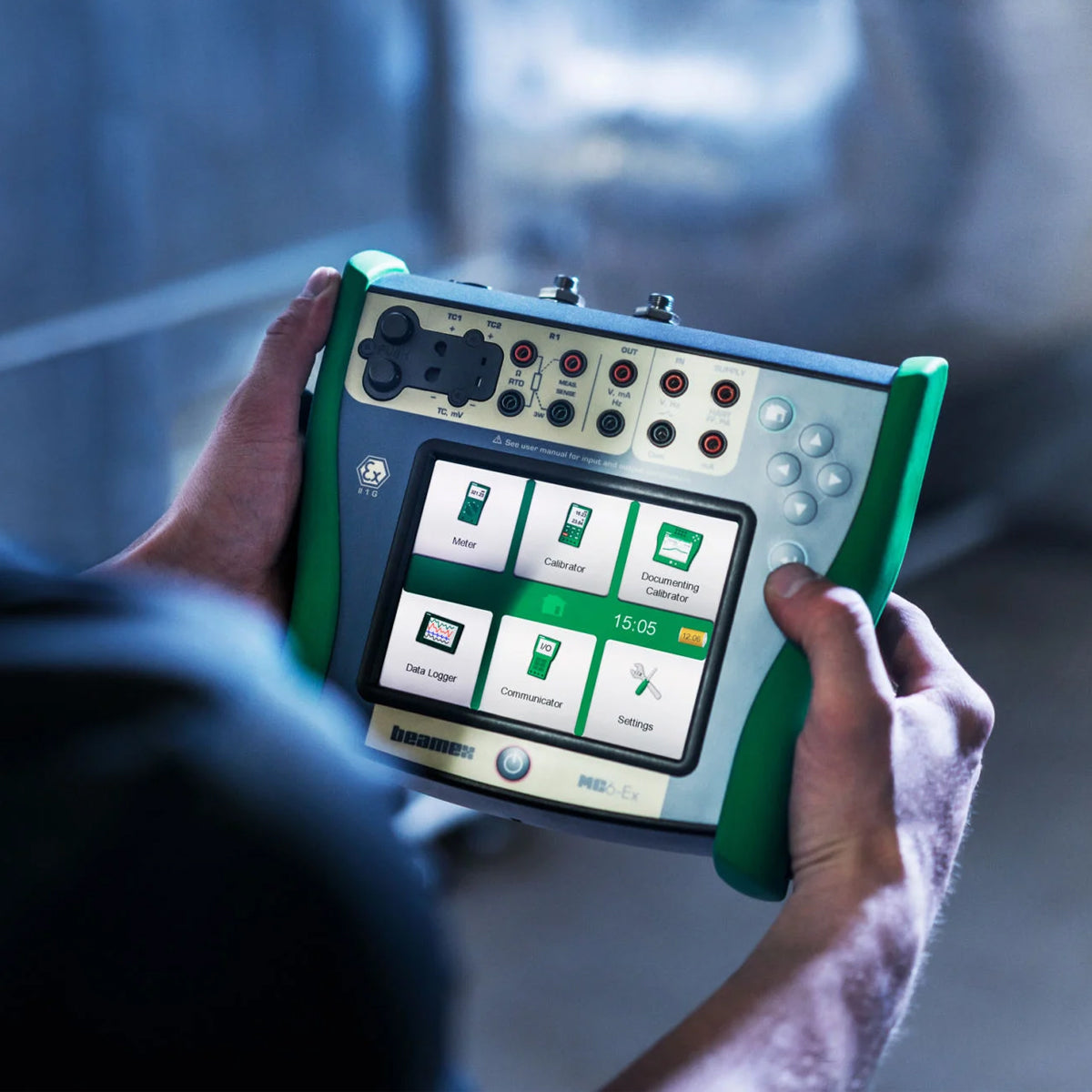 Person holding a handheld device with a digital display and control buttons.